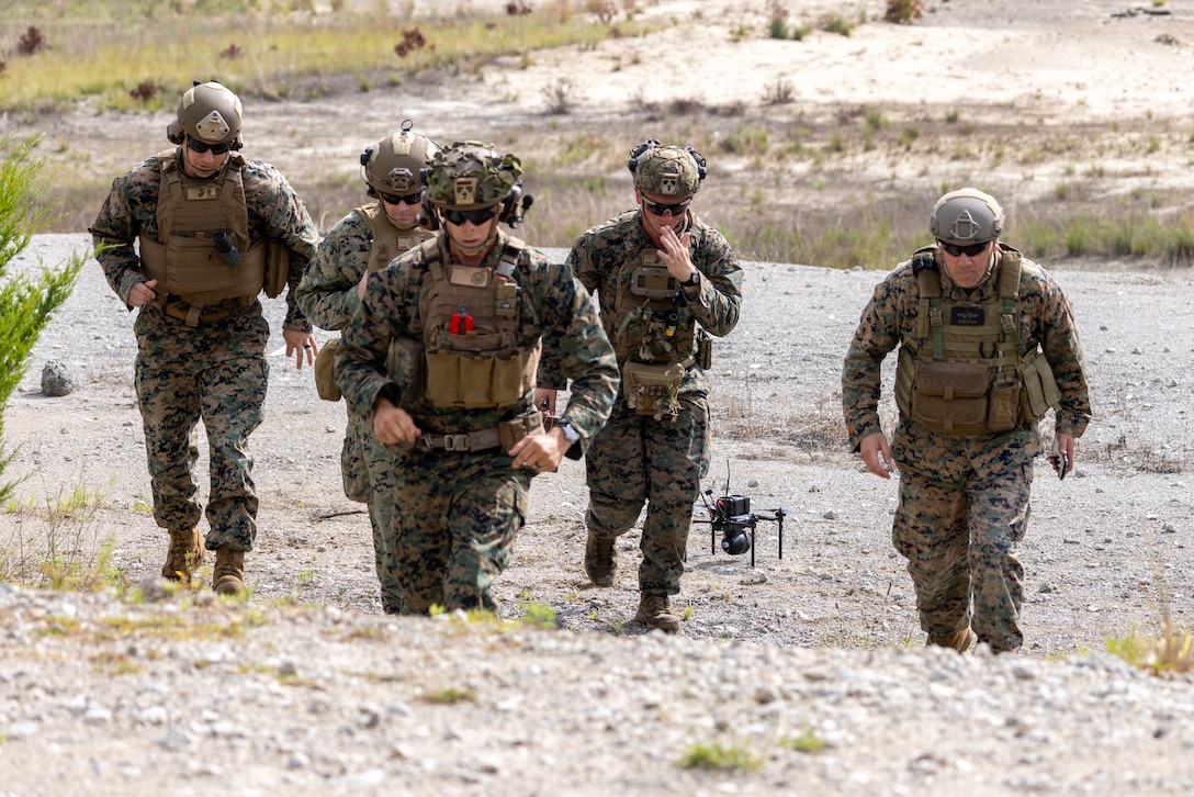 U.S. Marines with Advanced Infantry Training Battalion, School of Infantry – East run up range after preparing a Neros Archer small unmanned aircraft system (SUAS) for flight during a combined live-arms training event involving the employment of SUAS to deliver munitions on designated targets at Camp Lejeune, North Carolina, July 3, 2025. This event marked the first time munitions were employed from SUAS during a live-fire training exercise on Camp Lejeune, demonstrating the capability of integrating aerial strike capabilities at the tactical level. (U.S. Marine Corps photo by Cpl. Zachariah Ferraro)