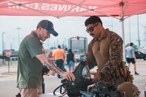 U.S. Marine Corps Staff Sgt. Jose Gonzalez, right, an explosive ordnance disposal technician with 2nd EOD, 8th Engineer Support Battalion, Marine Corps Base Camp Lejeune, North Carolina, shows a member of the community an EOD suit at Romeoville High School during Marine Week Chicago, Illinois, July 10, 2025. During Marine Week Chicago, Marines with Marine Corps Recruiting Command shared Marine Corps traditions with local high schools in honor of the Corps’ 250th birthday. The Marine Corps is celebrating its 250th birthday with six multi-day Marine Corps community events, called Marine Weeks, in six major cities across the country. Marine Weeks will include activations across each host city featuring aircraft, equipment, recruiting opportunities, and public engagements. (U.S. Marine Corps photo by Cpl. Sarah Grawcock)