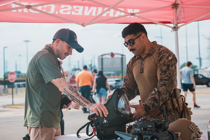 U.S. Marine Corps Staff Sgt. Jose Gonzalez, right, an explosive ordnance disposal technician with 2nd EOD, 8th Engineer Support Battalion, Marine Corps Base Camp Lejeune, North Carolina, shows a member of the community an EOD suit at Romeoville High School during Marine Week Chicago, Illinois, July 10, 2025. During Marine Week Chicago, Marines with Marine Corps Recruiting Command shared Marine Corps traditions with local high schools in honor of the Corps’ 250th birthday. The Marine Corps is celebrating its 250th birthday with six multi-day Marine Corps community events, called Marine Weeks, in six major cities across the country. Marine Weeks will include activations across each host city featuring aircraft, equipment, recruiting opportunities, and public engagements. (U.S. Marine Corps photo by Cpl. Sarah Grawcock)
