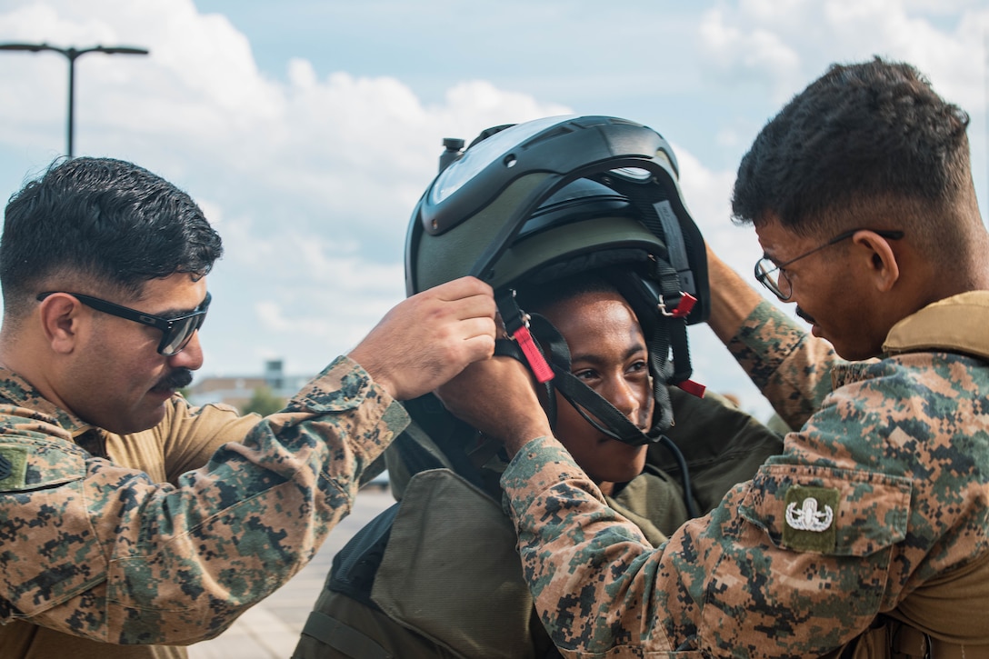 U.S. Marine Corps Staff Sgt. Jose Gonzalez, left and Staff Sgt. Jalen Riddle, right, both explosive ordnance disposal technicians with 2nd EOD, 8th Engineer Support Battalion, Marine Corps Base Camp Lejeune, North Carolina, puts an EOD advanced bomb suit on a member of the community at Romeoville High School during Marine Week Chicago, Illinois, July 10, 2025. During Marine Week Chicago, Marines with Marine Corps Recruiting Command shared Marine Corps traditions with local high schools in honor of the Corps’ 250th birthday. The Marine Corps is celebrating its 250th birthday with six multi-day Marine Corps community events, called Marine Weeks, in six major cities across the country. Marine Weeks will include activations across each host city featuring aircraft, equipment, recruiting opportunities, and public engagements. (U.S. Marine Corps photo by Cpl. Sarah Grawcock)