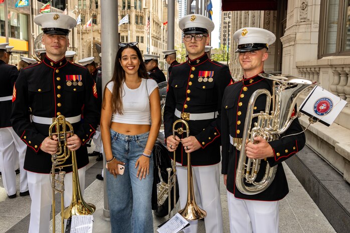 U.S. Marines with the Quantico Marine Band, assigned to Special Purpose Marine Air-Ground Task Force-250, and a Chicago resident pose for a photo during Marine Week Chicago, July 10, 2025. The opening ceremony signifies the start of Marine Week Chicago and represents the ethos of U.S. Marines to city residents. Throughout 2025, Marines across the globe will celebrate the 250th birthday of the Corps, commemorating service, sacrifice, and priding themselves on living ‘Semper Fidelis’ or ‘Always Faithful’ to their nation and to each other. (U.S. Marine Corps photo by Lance Cpl. Elijua Guel)