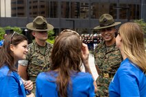 U.S. Marine Corps Staff Sgt. Joshua Pontius, a drill instructor with Instructional Training Company, Support Battalion, left, and U.S. Marine Corps Sgt. Rasheed Awyan, a drill instructor with Echo company, 2nd Recruit Training Battalion, both assigned to Marine Corps Recruit Depot San Diego, interact with the Make-A-Wish staff during a ceremony for Jamaria Peters at the Willis Tower for Marine Week Chicago, July 11, 2025. The event featured a performance from the Marine Corps Silent Drill Platoon, music from the Quantico Marine Band, and the appearance of drill instructors from the recruit depot. This year, the Marine Corps will celebrate two and a half centuries of serving the nation with honor, courage, and commitment. (U.S. Marine Corps photo by Lance Cpl. Elijua Guel)