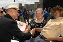 U.S. Marine Corps Col. J.J. Wilson, the commanding officer of Special Purpose Marine Air-Ground Task Force-250, gives a certificate of appreciation to Jamaria Peters, a Make-A-Wish recipient, during a ceremony for Peters at the Willis Tower for Marine Week Chicago, July 11, 2025. The event featured a performance from the Marine Corps Silent Drill Platoon, music from the Quantico Marine Band, and the appearance of drill instructors from Marine Corps Recruit Depot San Diego. This year, the Marine Corps will celebrate two and a half centuries of serving the nation with honor, courage, and commitment. (U.S. Marine Corps photo by Lance Cpl. Elijua Guel)