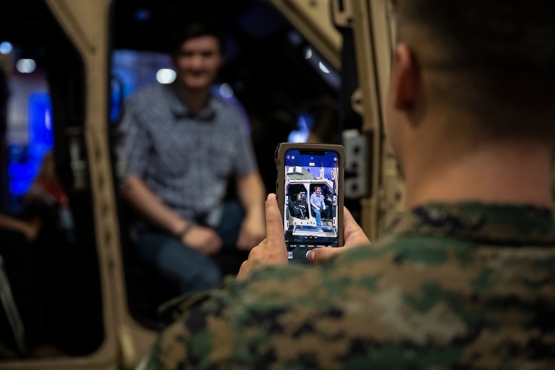 A U.S. Marine takes a photo for a man and his son inside a Joint Light Tactical Vehicle inside the Music City Center in Nashville, Tennessee, June 5, 2025. Marines set up multiple equipment displays and recruiting booths during Marine Week to engage with the community of Nashville. Throughout 2025, Marines across the globe will celebrate the 250th birthday of the Corps, commemorating, service, sacrifice, and priding themselves on living ‘Semper Fidelis’ or ‘Always Faithful’ to their nation and to each other. (U.S. Marine Corps photo by Cpl. Vincent Needham)