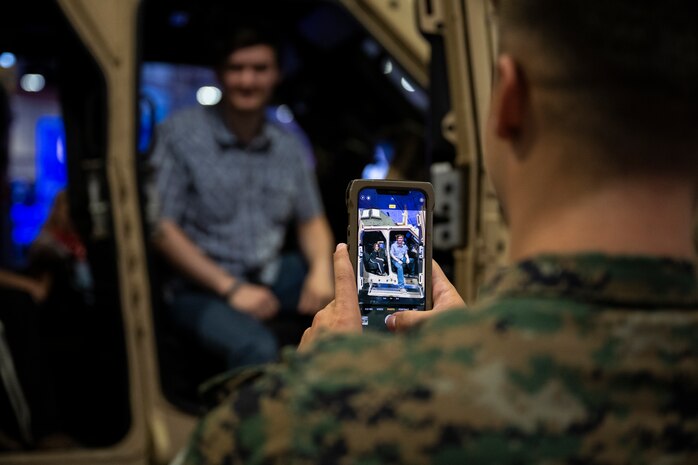 A U.S. Marine takes a photo for a man and his son inside a Joint Light Tactical Vehicle inside the Music City Center in Nashville, Tennessee, June 5, 2025. Marines set up multiple equipment displays and recruiting booths during Marine Week to engage with the community of Nashville. Throughout 2025, Marines across the globe will celebrate the 250th birthday of the Corps, commemorating, service, sacrifice, and priding themselves on living ‘Semper Fidelis’ or ‘Always Faithful’ to their nation and to each other. (U.S. Marine Corps photo by Cpl. Vincent Needham)