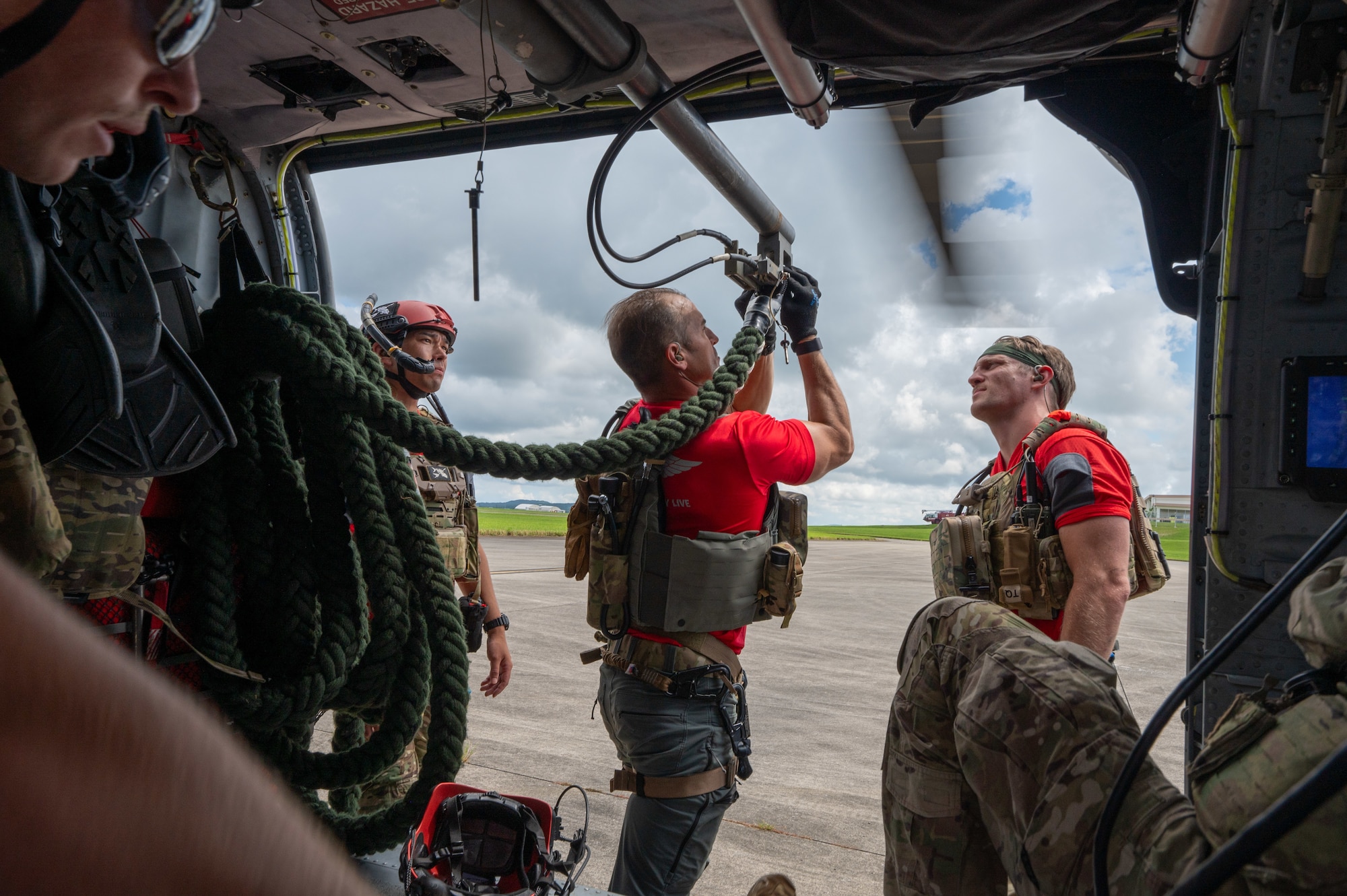 military members fasten a rope on a helicopter