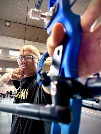Sgt. 1st Class Hong is working on pulling back on the bow string to get used to the tension.
