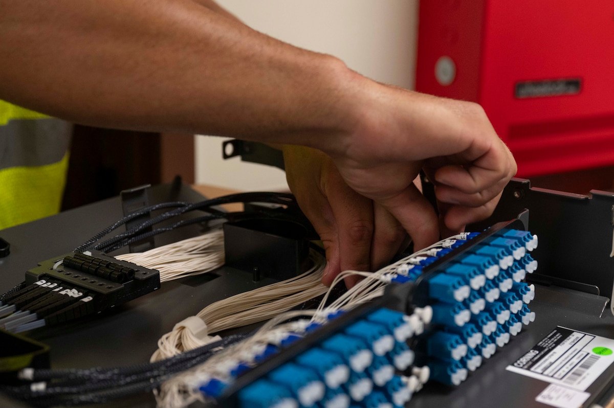 U.S. Air National Guard Staff Sgt. Jonathan Ziemer, 210th Engineering Installation Squadron cable technician, configures a fiber optic rack-mount connector at Joint Base Pearl Harbor-Hickam, Hawaii, July 9, 2025. This installation is part of the Fiber Deep project; a strategic initiative designed to enhance base communications and bolster cyber defense capabilities. (U.S. Air Force photo by Senior Airman Melody Bordeaux)