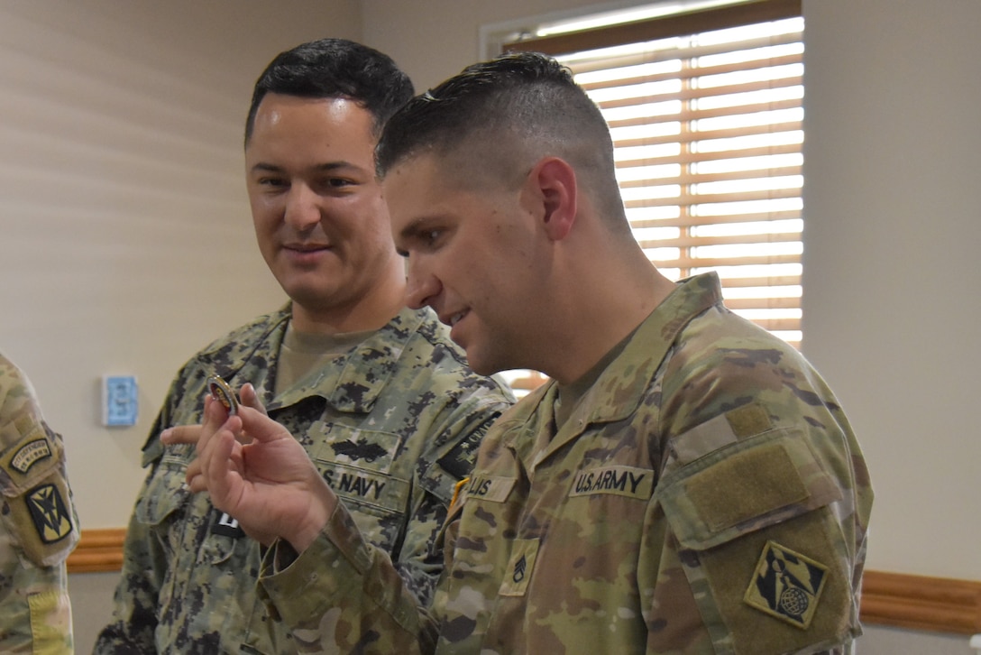 Staff Sgt. Cullen Ellis, quality assurance representative, U.S. Army Corps of Engineers – Far East District, receives a commander's coin from a Navy counterpart.