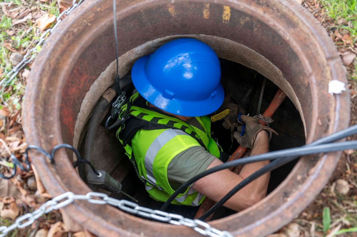 U.S. Air National Guard Staff Sgt. Johnathan Day, 205th Engineering Installation Squadron cable technician, prepares to install a fiber optic cable in an underground utility access point on Joint Base Pearl Harbor-Hickam, Hawaii, July 9, 2025. This installation is part of the Fiber Deep project; a strategic initiative designed to enhance base communications and bolster cyber defense capabilities. (U.S. Air Force photo by Senior Airman Melody Bordeaux)