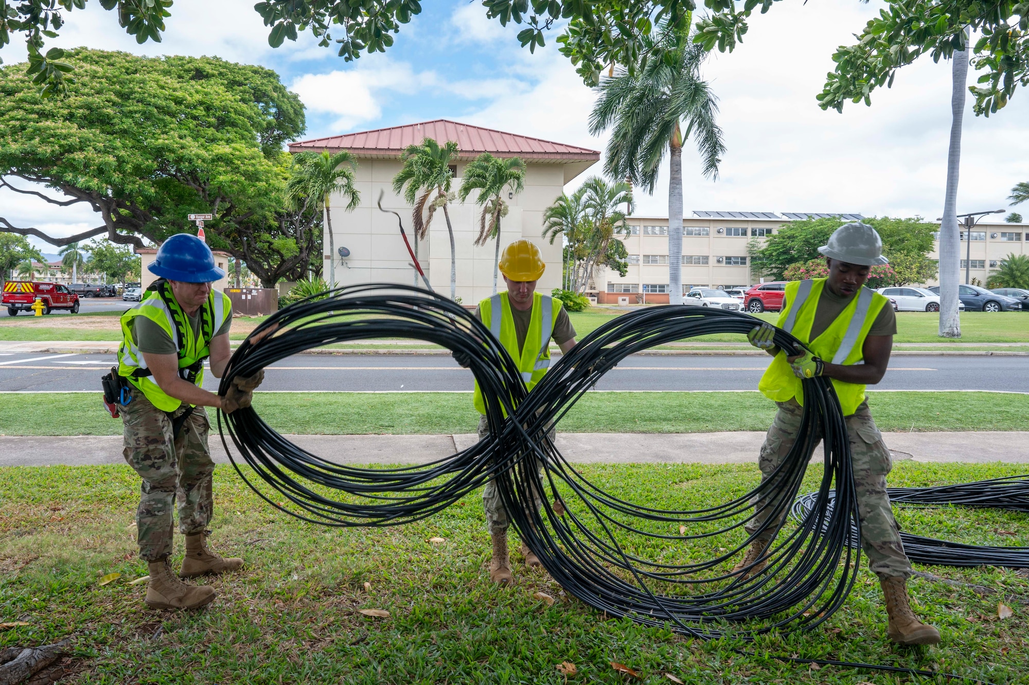 U.S. Air National Guard Staff Sgt. Johnathan Day, left, 205th Engineering Installation Squadron, Staff Sgt. Myles Clarke, center, 210th EIS, and Staff Sgt. Devante Richardson, 202nd EIS, prepare a coiled fiber optic cable for installation on Joint Base Pearl Harbor-Hickam, Hawaii, July 9, 2025. The Fiber Deep project underway at Joint Base Pearl Harbor-Hickam, a transformation spearheaded by an U.S. Air National Guard engineering installation team, is set to save approximately $10 million dollars, while simultaneously fortifying against cyber threats. (U.S. Air Force photo by Senior Airman Melody Bordeaux)