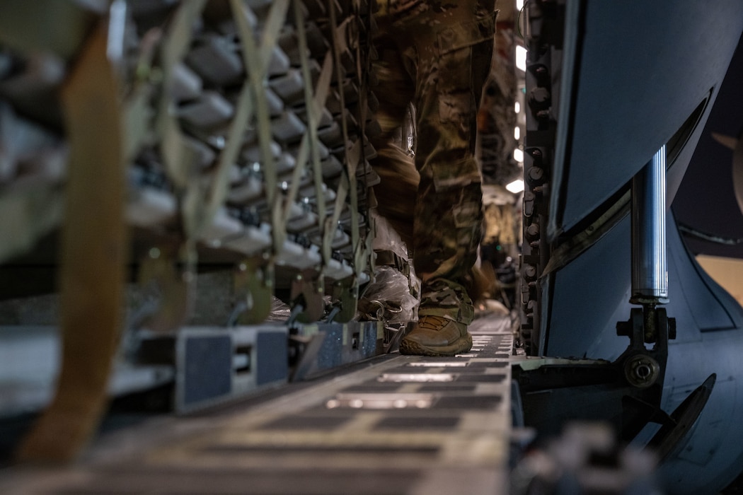 A U.S. Airman assigned to the 758th Expeditionary Airlift Squadron, walks on the ramp during cargo upload within the U.S. Central Command area of responsibility, June 15, 2025. Loading crews execute rapid resource deployments to enhance resiliency and sustain combat operations in disputed environments. (U.S. Air Force photo by Senior Airman Amanda Jett)