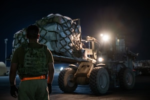 U.S. Air Force Senior Airman Aaron Hernandez, 379th Expeditionary Air Base Group ramp specialist, directs a forklift during cargo upload within the U.S. Central Command area of responsibility, June 14, 2025. Loading crews execute rapid resource deployments to enhance resiliency and sustain combat operations in dynamic environments. (U.S. Air Force photo by Senior Airman Amanda Jett)