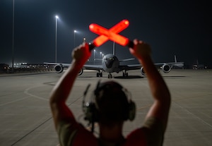 U.S. Air Force Staff Sgt. Brock Thompson, 758th Expeditionary Airlift Squadron crew chief, prepares to marshall a KC-135 Stratotanker within the U.S. Central Command area of responsibility, June 12, 2025. The KC-135 provides aerial refueling capabilities throughout the AOR in support of coalition partners and aircraft from joint forces in order to generate combat airpower for the CENTCOM region. (U.S. Air Force photo by Senior Airman Amanda Jett)