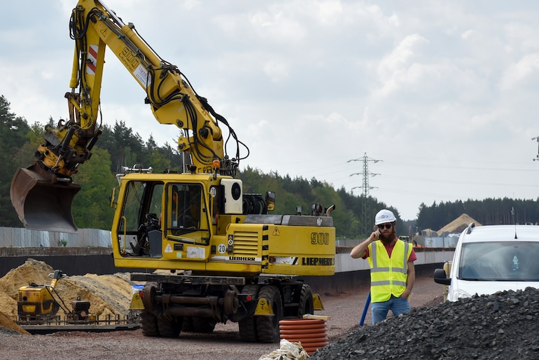 man on phone next to heavy equipment