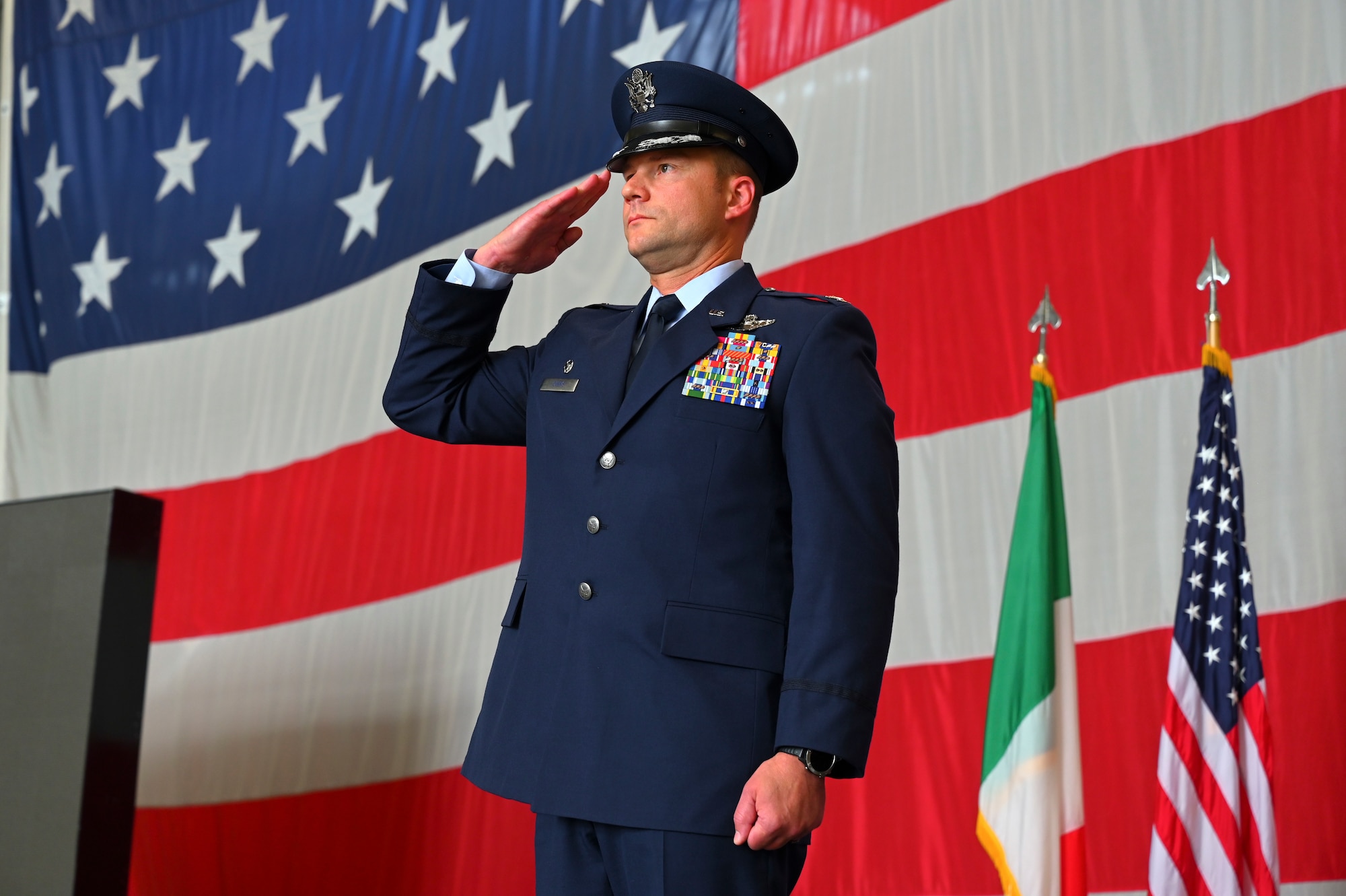 Col. Beau Diers saluting in front of an American flag.