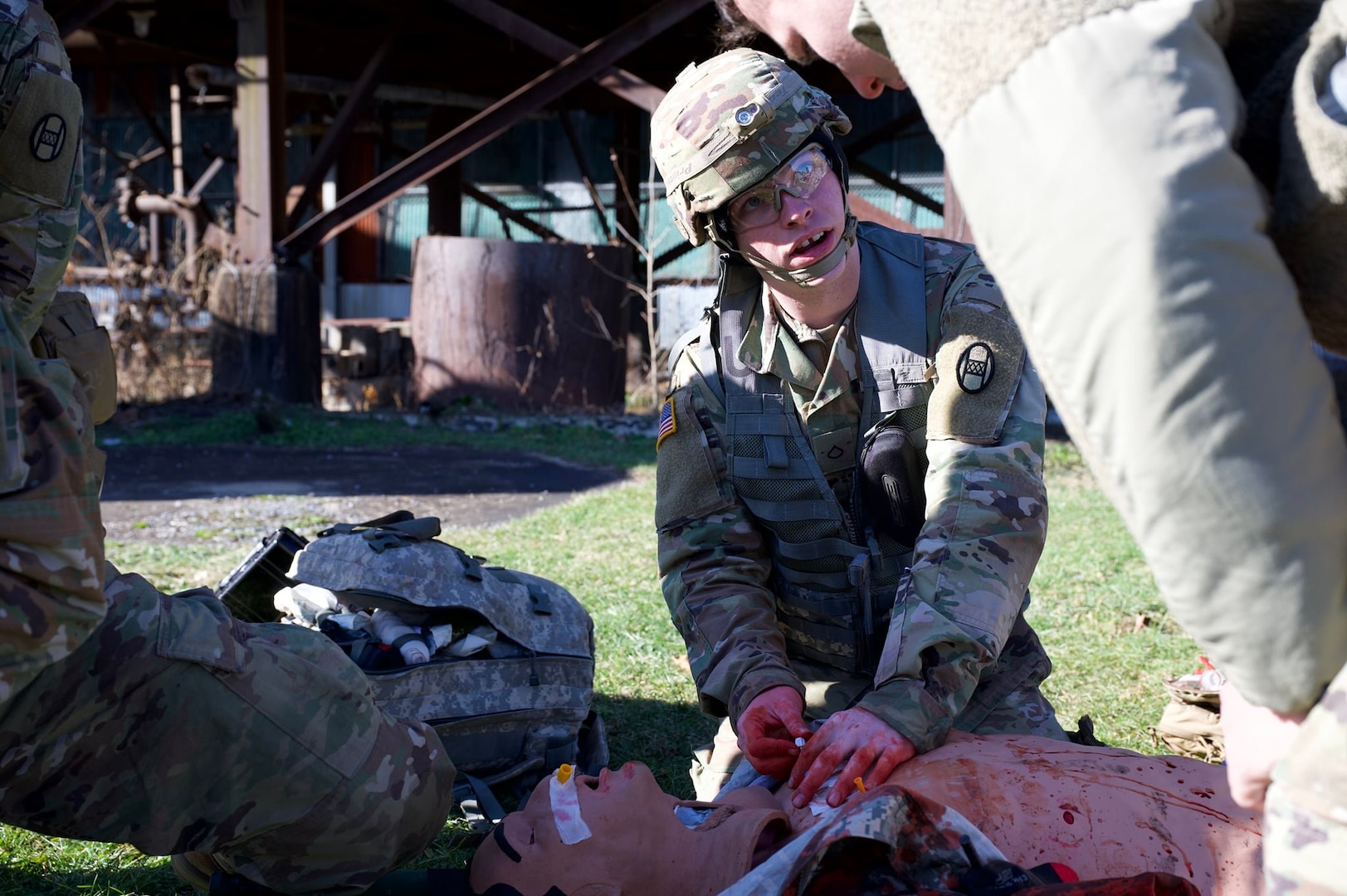 a soldier works on a "bloodied" medical dummy outside