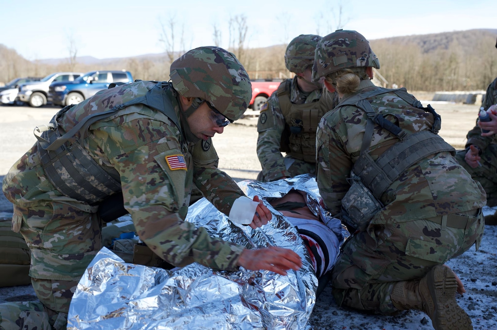 soldiers wrap a medical dummy in heat blankets outside