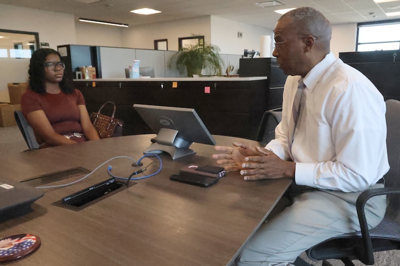 Man sitting at table talking to a woman.