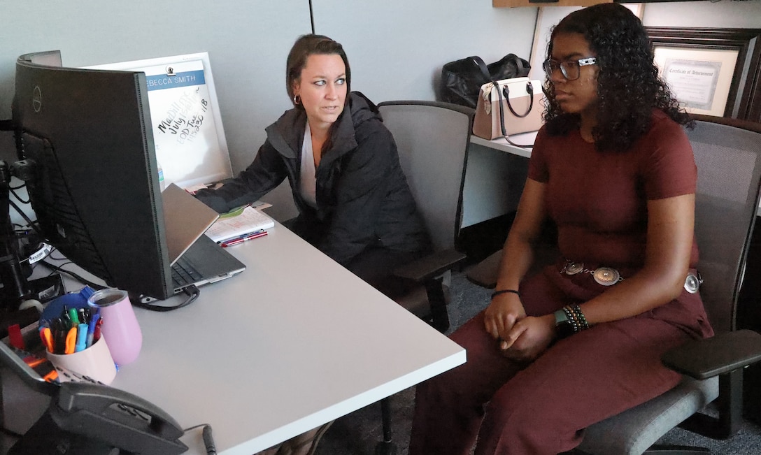 Woman showing a woman something on a computer.