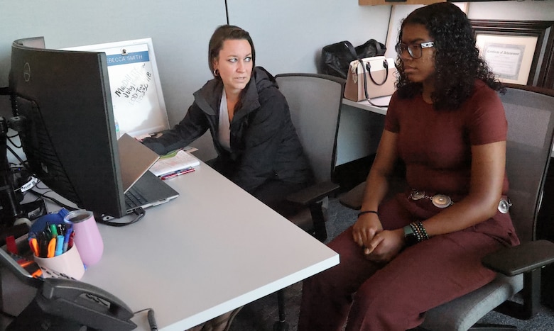 Woman showing a woman something on a computer.