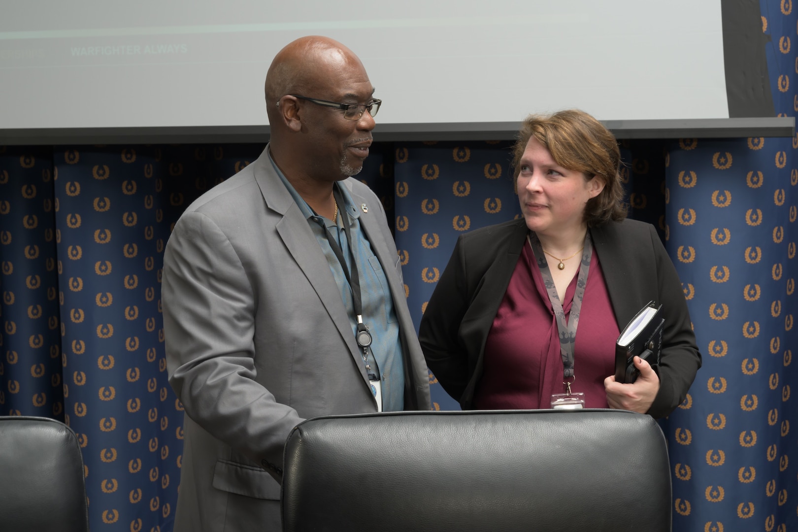 A man and a woman talk side by side in a conference room