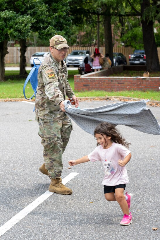 Airman throws a blanket over daughter. (U.S. Air Force photo by Airman 1st Class Thalia Bonte)