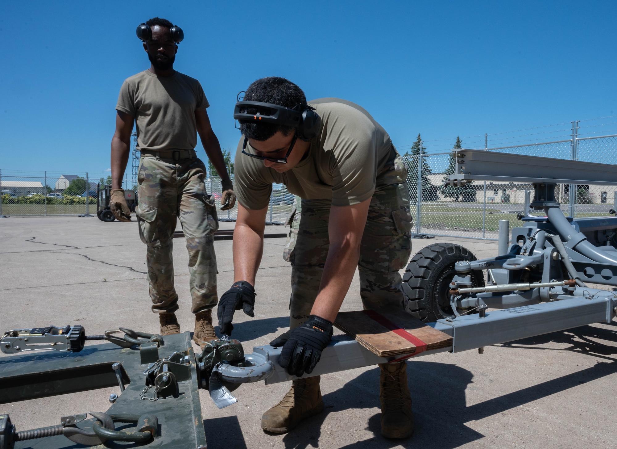 Senior Airman Jonathan Gonzalez-Rodriguez, 5th Logistics Readiness Squadron (5LRS)  air transportation specialist, attaches a trailer to a forklift to bring cargo to a C-5M Super Galaxy at Minot Air Force Base, North Dakota, July 1, 2025. The 5LRS air transportation function is vital to the mission at Minot AFB because it enables the timely delivery of equipment and supplies to missions in and outside of the base. (U.S. Air Force photo by Airman 1st Class Wesley Davies)