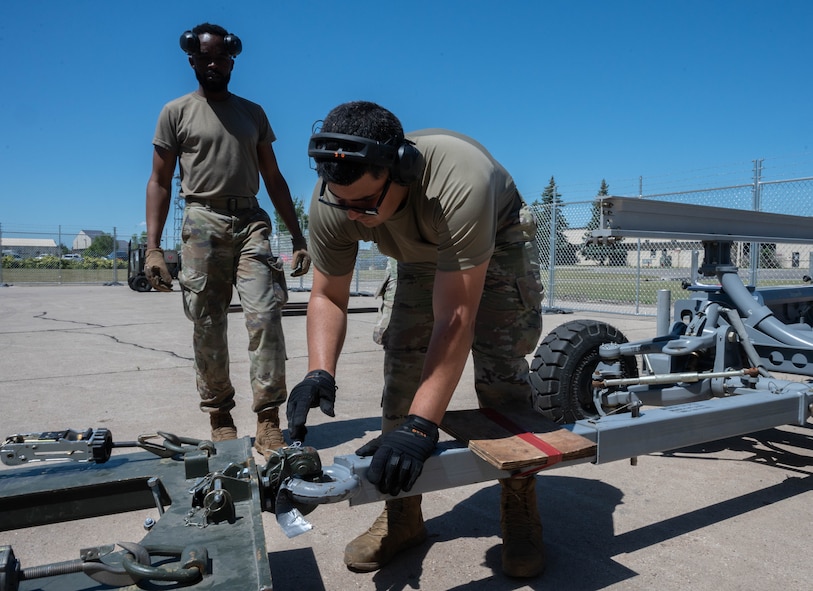Senior Airman Jonathan Gonzalez-Rodriguez, 5th Logistics Readiness Squadron (5LRS)  air transportation specialist, attaches a trailer to a forklift to bring cargo to a C-5M Super Galaxy at Minot Air Force Base, North Dakota, July 1, 2025. The 5LRS air transportation function is vital to the mission at Minot AFB because it enables the timely delivery of equipment and supplies to missions in and outside of the base. (U.S. Air Force photo by Airman 1st Class Wesley Davies)