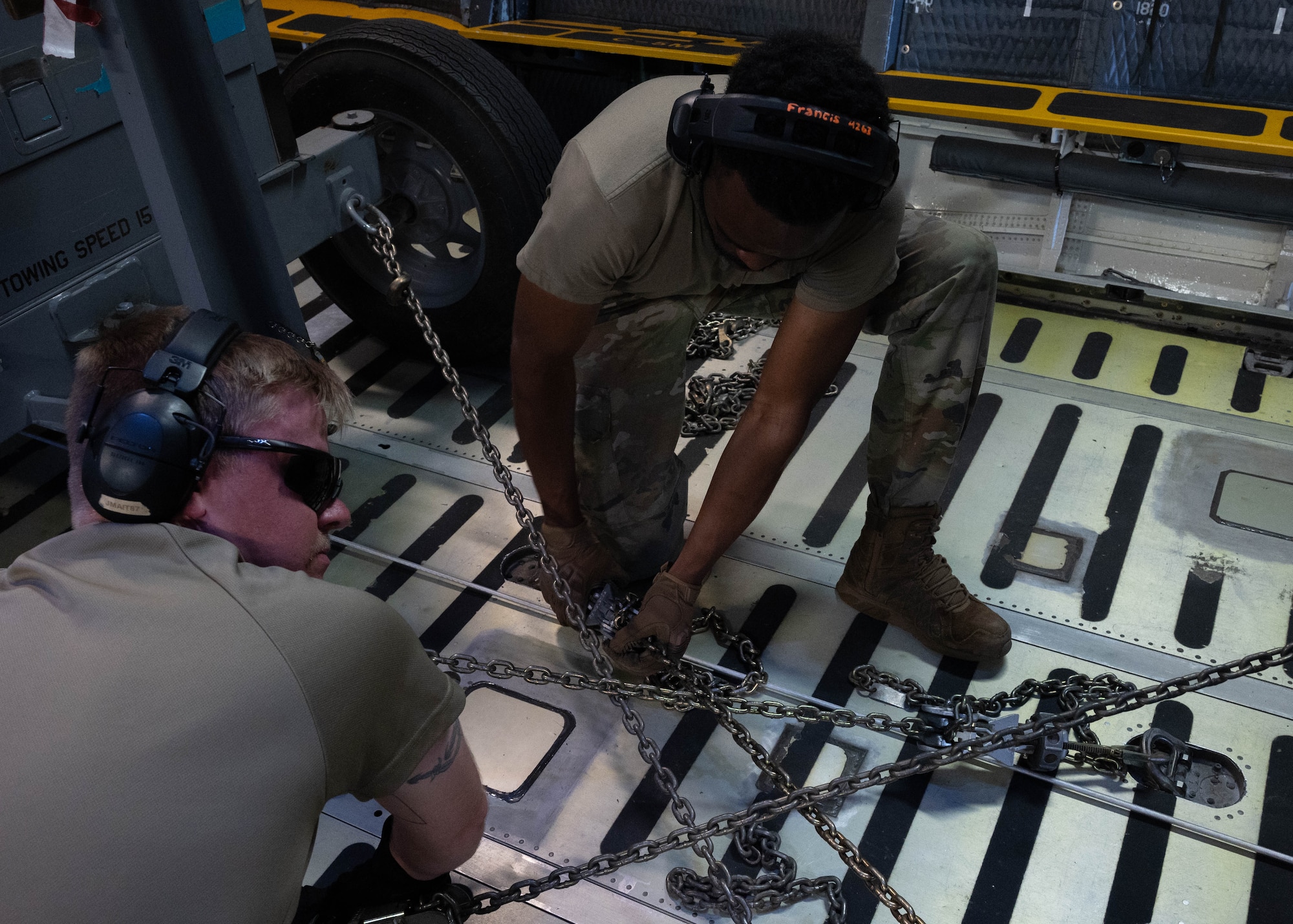 Airmen from the 5th Logistics Readiness Squadron (5LRS) tie cargo into place with chains on a C-5M Super Galaxy at Minot Air Force Base, North Dakota, July 1, 2025. The 5LRS air transportation function is vital to the mission at Minot Air Force Base because it enables the timely delivery of equipment and supplies to missions in and outside of the base. (U.S. Air Force photo by Airman 1st Class Wesley Davies)