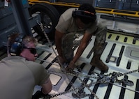 Airmen from the 5th Logistics Readiness Squadron (5LRS) tie cargo into place with chains on a C-5M Super Galaxy at Minot Air Force Base, North Dakota, July 1, 2025. The 5LRS air transportation function is vital to the mission at Minot Air Force Base because it enables the timely delivery of equipment and supplies to missions in and outside of the base. (U.S. Air Force photo by Airman 1st Class Wesley Davies)