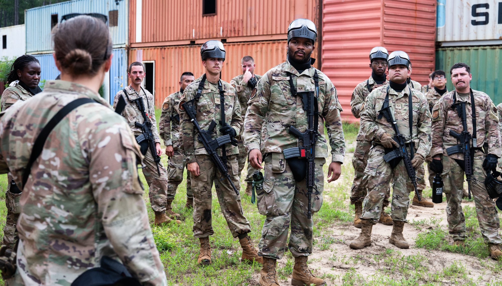Airmen in uniform huddle in a group as they listen to feedback.