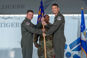 Two people standing on a stage holding a guidon.
