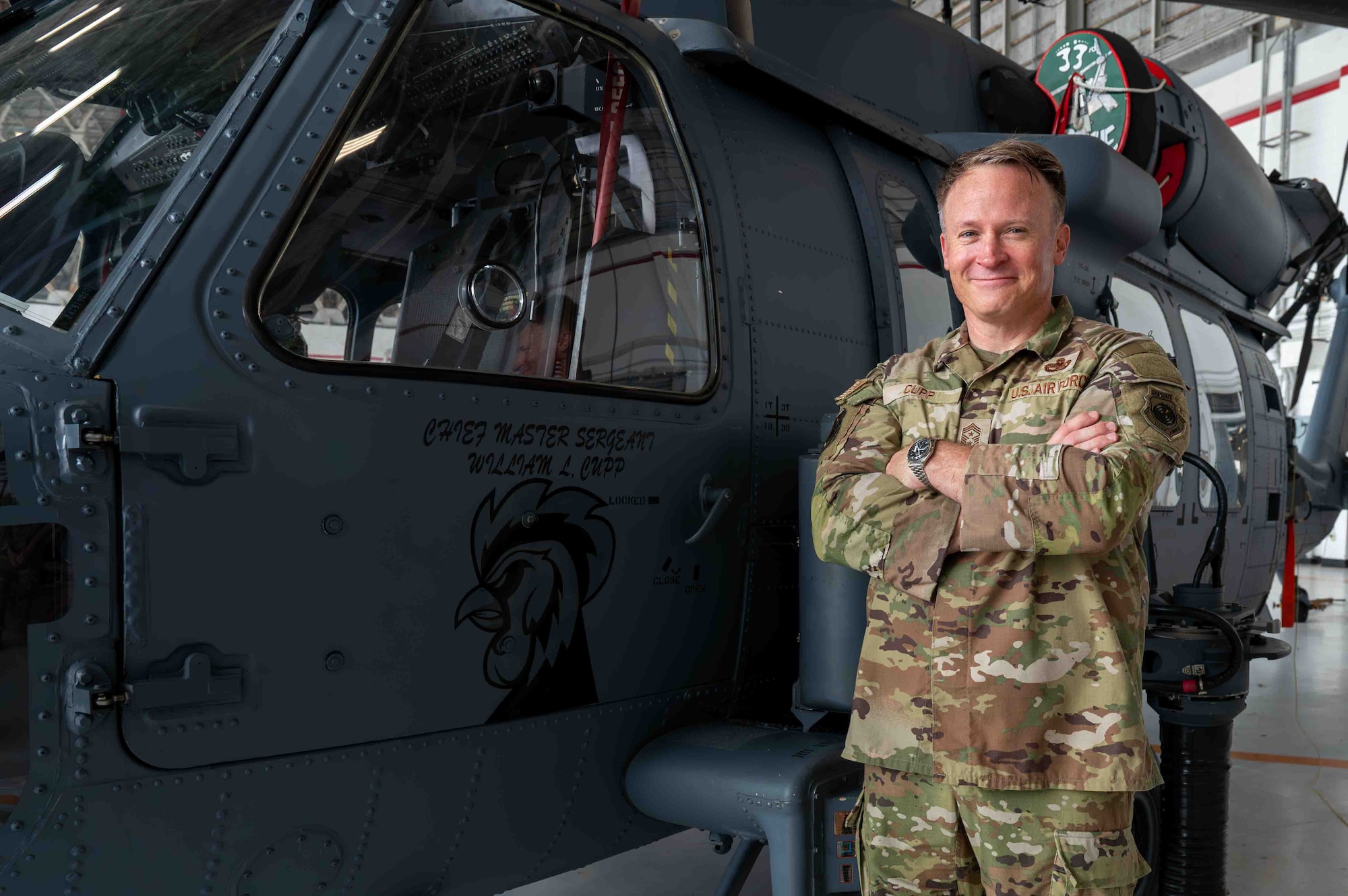 Service member pose in front of a helicopter.