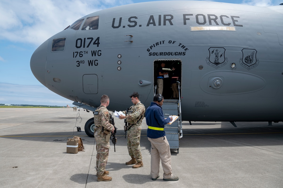 U.S. Air Force defenders assigned to the 35th Security Forces Squadron review paperwork from an incoming C-17 Globemaster III during exercise Resolute Force Pacific (REFORPAC) 2025 at Misawa Air Base, Japan, July 11, 2025. REFORPAC is part of the first-in-a-generation Department-Level Exercise series, employing more than 400 Joint and coalition aircraft and more than 12,000 members at more than 50 locations across 3,000 miles. (U.S. Air Force photo by Senior Airman Brittany Russell)