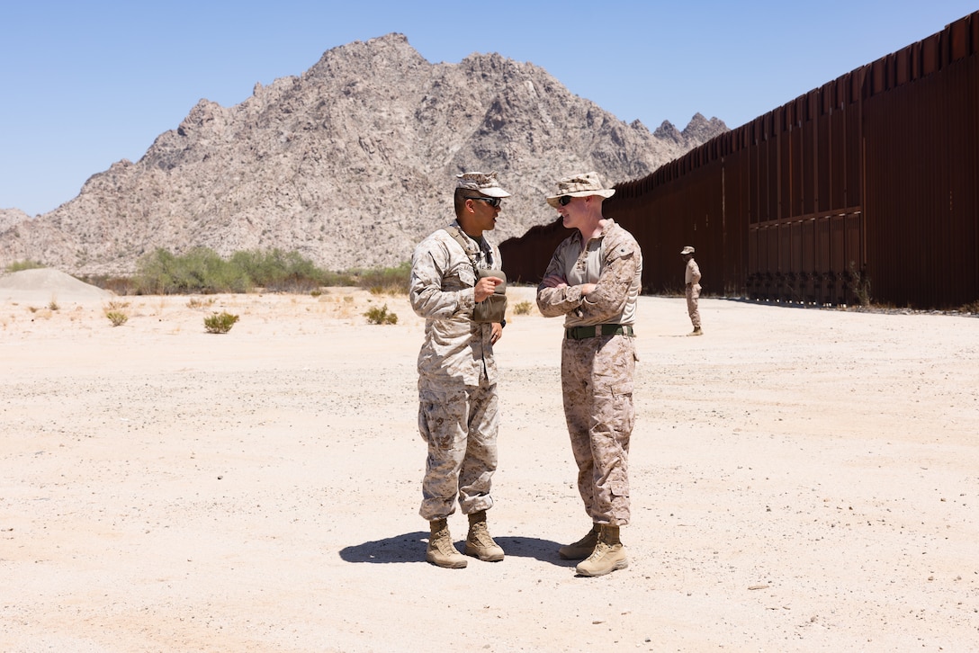 U.S. Marine Corps Lt. Col. Tyrone Barrion, left, commanding officer of Task Force Sapper, and Lt. Col. Colin Graham, commanding officer of Task Force Forge, discuss their mission at the southern border barrier in preparation for a unit rotation in support of Joint Task Force-Southern Border, in the Yuma Sector, July 12, 2025.  Task Force Forge comprises 500 Marines and Sailors from Combat Logistics Battalion 15, 1st Marine Logistics Group, I Marine Expeditionary Force, tasked to support the Joint Task Force-Southern Border mission with engineering and logistics capabilities. Joint Task Force-Southern Border executes full-scale, agile, and all-domain operations in support of U.S. Customs and Border Protection to protect the territorial integrity of the United States and achieve 100% operational control of the southern border. (U.S. Marine Corps photo by Sgt. Mary Torres)