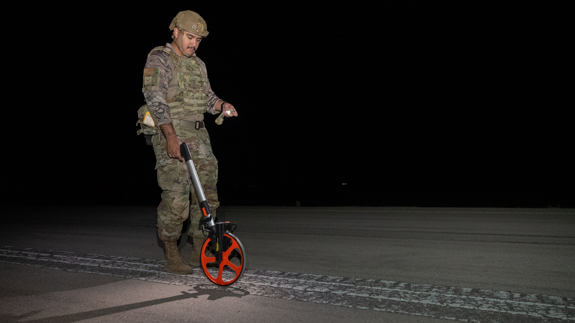 An Airman takes measurements of a tactical airfield.
