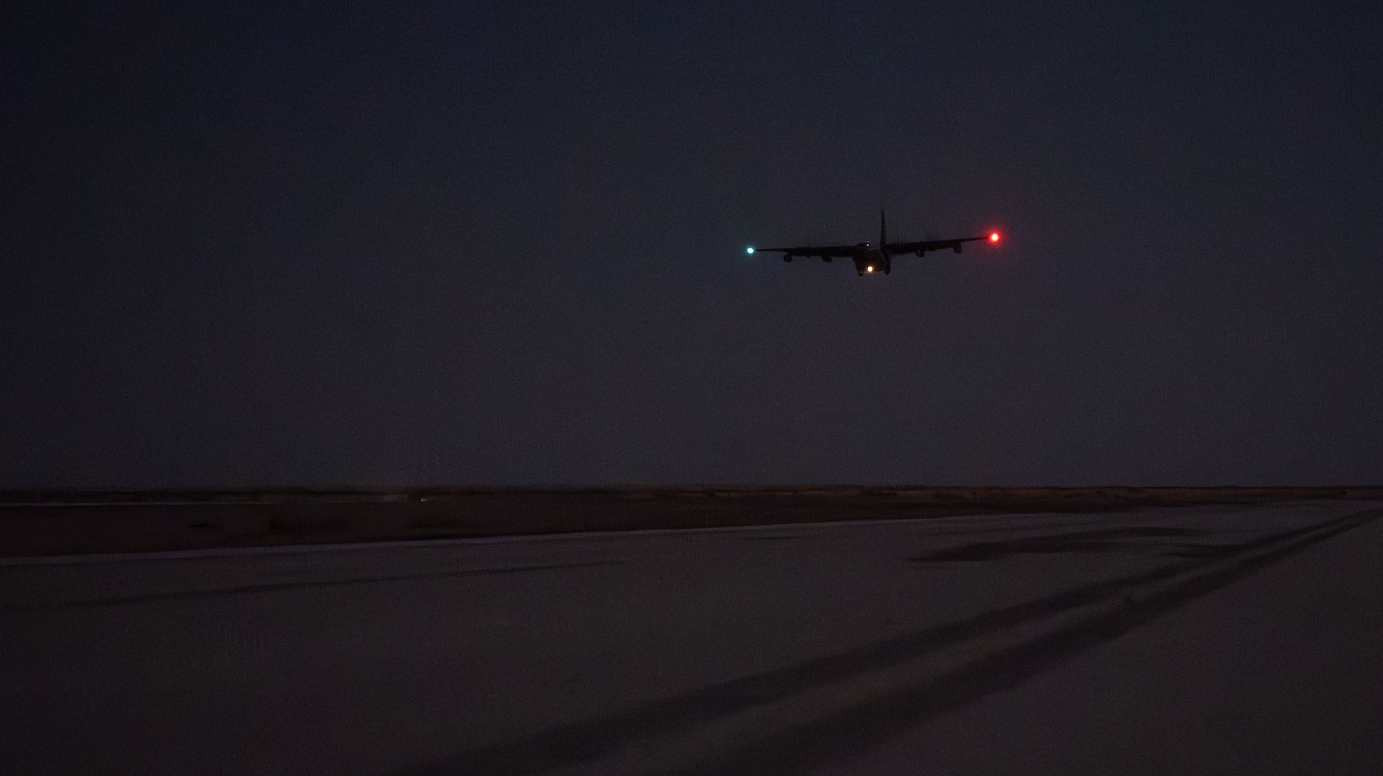 A U.S. Air Force HC-130J Combat King II assigned to the 26th Expeditionary Rescue Squadron flies over a tactical airfield.