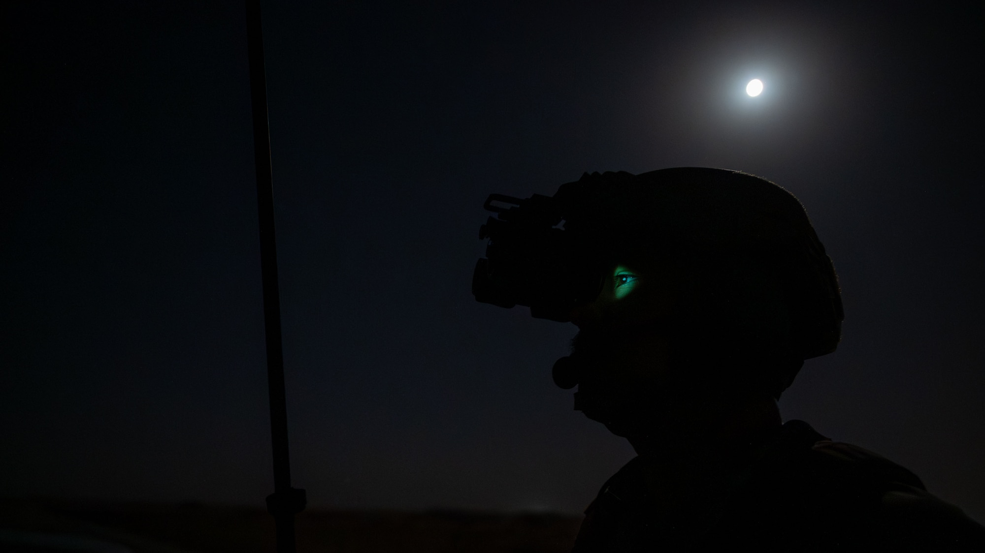 A silhouette of an Airmen wearing night-vision goggles.