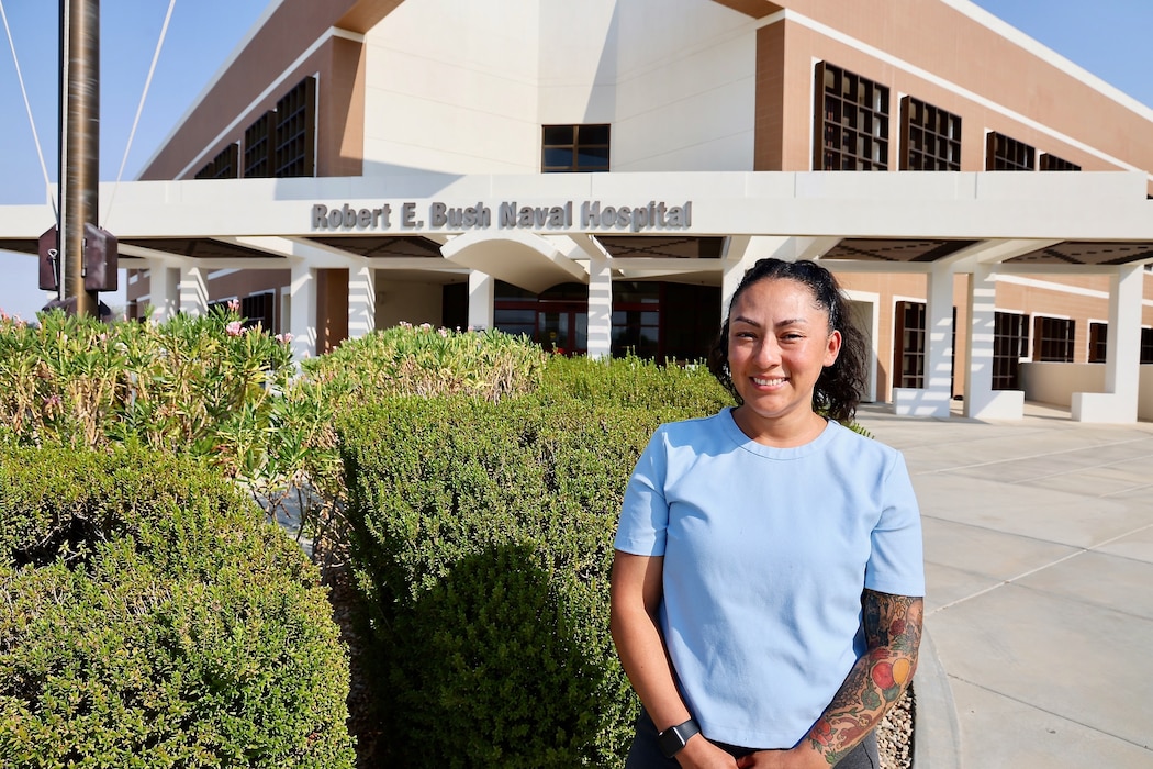 Jessica Hernandez, Physical Evaluation Board Liaison (PEBLO) at Navy Medicine Readiness and Training Command (NMRTC) Twentynine Palms, stands in front of Robert E. Bush Naval Hospital, where she was recognized for her outstanding contributions to medical readiness and disability case management. In May, Hernandez received the 2025 Department of the Navy Disability Evaluation System (DON DES) “All Star” Award for leading efforts that improved data accuracy by 50%, streamlined medical evaluation board processing, and enhanced outcomes for more than 12,000 service members across three geographically dispersed units — all while serving as the sole PEBLO (U.S. Navy photo by Christopher C. Jones, NHTP/NMRTC Twentynine Palms public affairs officer).