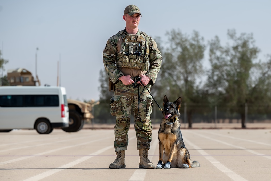 A military working dog handler and an MWD pose for a photo