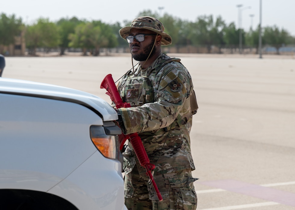 USAF Airman with a mock weapon opens a vehicle hood
