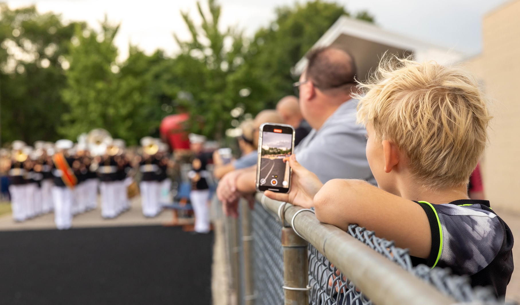 A child records the Quantico Marine Band’s performance during Marine Week at Romeoville High School, Romeoville, Illinois, July 10, 2025. Marine Week Chicago celebrated 250 years of the Marine Corps at Romeoville High School with static displays, a silent drill performance, music, games, and flight simulators. (U.S. Marine Corps photo by Lance Cpl. Harleigh Faulk)