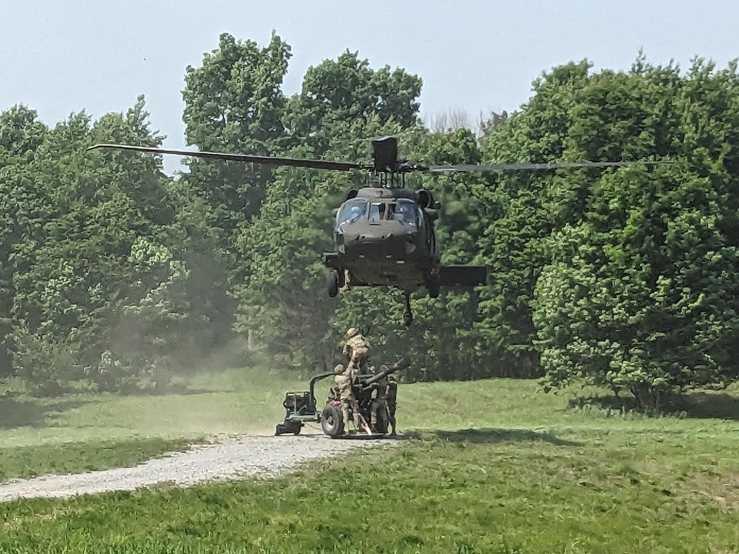 A UH-60M Black Hawk helicopter assigned to the New York National Guard's A Company, 3rd Battalion, 142nd Aviation, prepares to lift an M-117 howitzer belonging to the 1st Battalion, 258th Field Artillery during a training exercise at Fort Drum, New York on June 8, 2025.