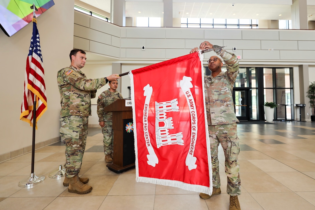 Outgoing ERDC Commander Col. Dr. Christian Patterson attaches the Army Superior Unit Award streamer to the USACE flag.