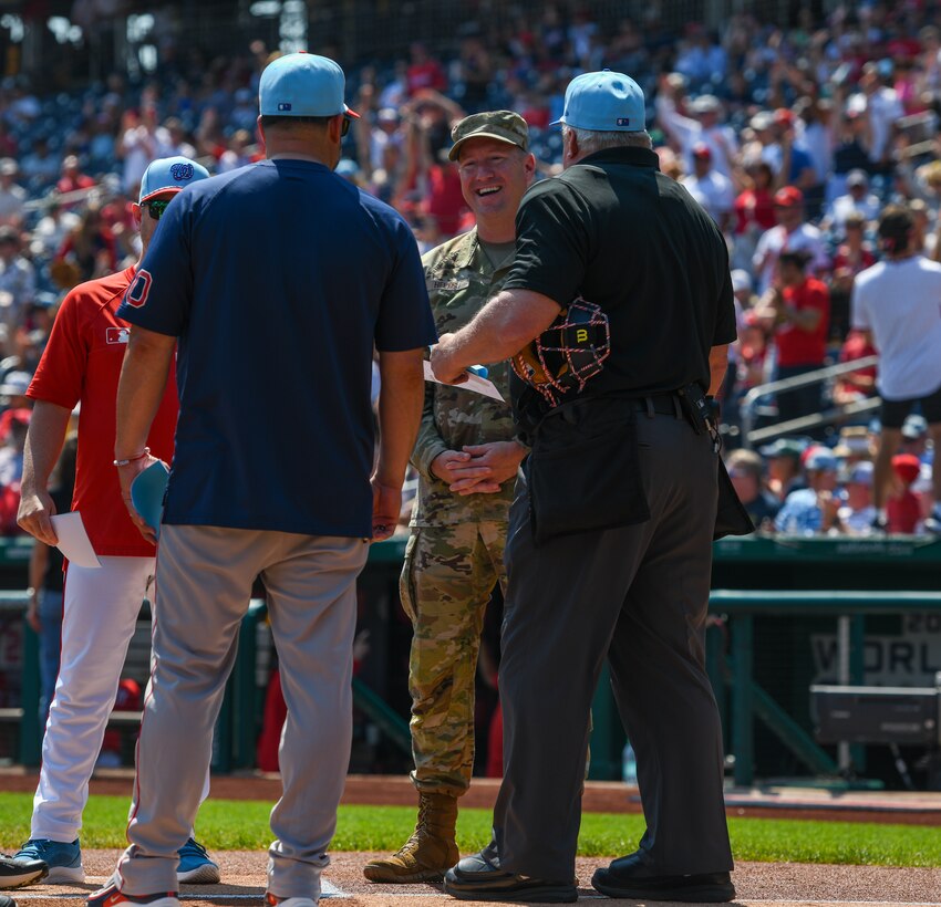 Umpires stand at the pitcher's mound.