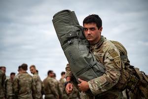 U.S. Army Pvt. Marcus Puentes, a combat medic assigned to the 3rd Battalion, 509th Parachute Infantry Regiment, 2nd Infantry Brigade Combat Team (Airborne), 11th Airborne Division, carries equipment during a personnel deployment function line in support of Talisman Sabre at Joint Base Elmendorf-Richardson, Alaska, July 13, 2025.