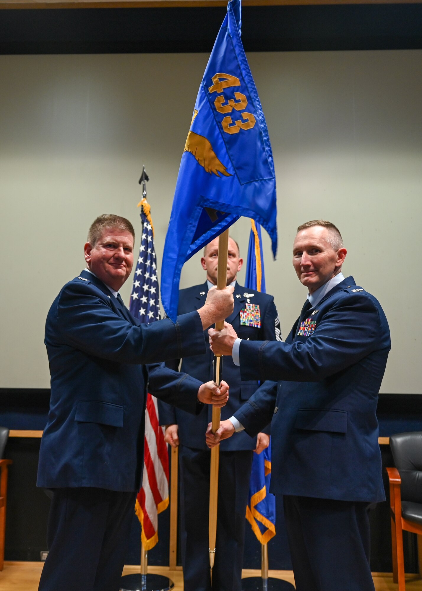 Col. Jeremy Patrick (left), 433rd Operations Group commander, hands the 433rd Aeromedical Evacuation Squadron guidon to Col. David Bailey (right), 433rd AES Commander, during an assumption of command ceremony at Joint Base San Antonio-Lackland, Texas, July 12, 2025.