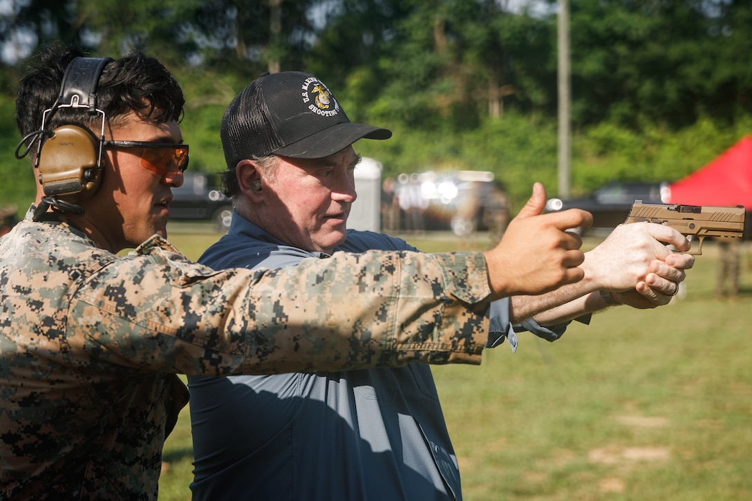 U.S. Marine Corps Staff Sgt. Payton Garcia, a bulk fuel specialist, instructor and competitor with the Marine Corps Shooting Team, left, coaches John C. Phelan, the 79th Secretary of the Navy, on firing the M18 pistol during live-fire training at Weapons Training Battalion, Marine Corps Base Quantico, Virginia, June 25, 2025. The visit highlighted how the Marine Corps is building on Weapons Training Battalion’s legacy and expertise in precision weaponry to drive innovation in small-arms capabilities and first-person view attack drones. The event also identified key areas where the Secretary’s support could enhance the lethality of both the Marine Corps and the Department of the Navy. (U.S. Marine Corps photo by Cpl. Joshua Barker)