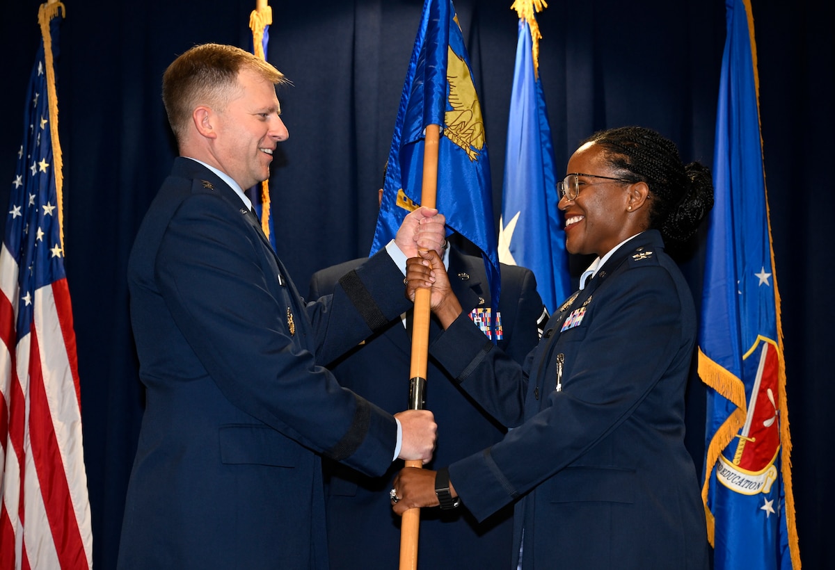 Maj. Gen. Parker H. Wright, commander of the Curtis E. LeMay Center for Doctrine Development and Education, passes the Thomas N. Barnes Center for Enlisted Education flag to Col. Stephanie Q. Wilson during an Assumption of Command ceremony at Maxwell Air Force Base, Alabama, July 14, 2025. (U.S. Air Force photo by Brian Ferguson)